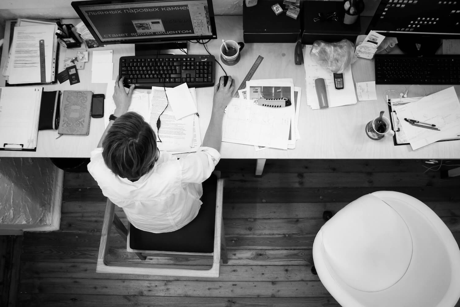 secretary working on a computer at a messy desk