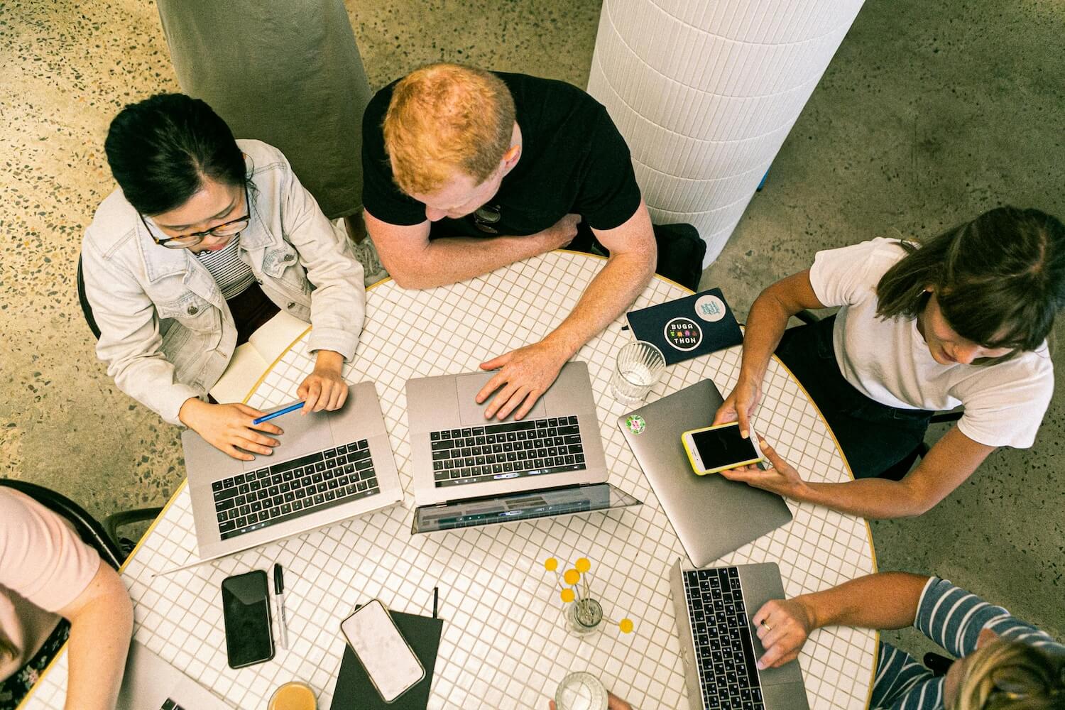 a team of coworkers working together at a table with laptops